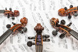 Fünf Geigenköpfe und Notenblätter als Hintergrund