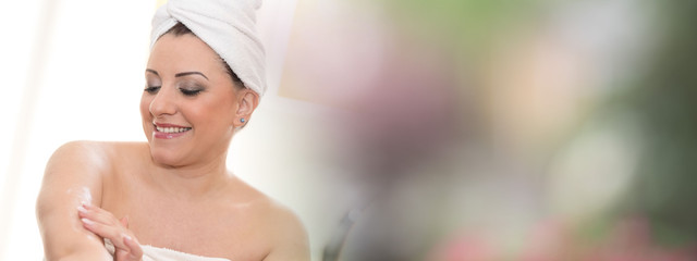 Portrait of smiling young woman applying moisturizing cream