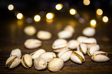 Pistachios on a wooden table with blurred lights in the background