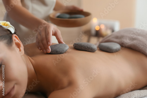 Photo Beautiful young woman getting hot stone massage in spa salon