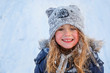 Beautiful little girl wearing navy jacket and knitted hat playing in a snowy winter park. Child playing with snow in winter. Kid play and jump in snowy forest. Family vacation with child in mountains	