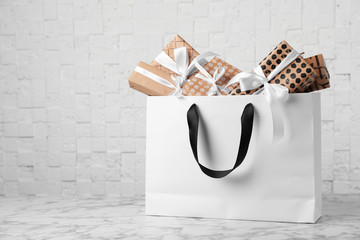 Wall Mural - Paper shopping bag with handles full of gift boxes on table. Mock up for design