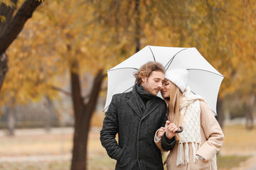 Sticker - Young romantic couple with umbrella in park on autumn day