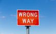 © markrhiggins - Wrong way road sign isolated against sky