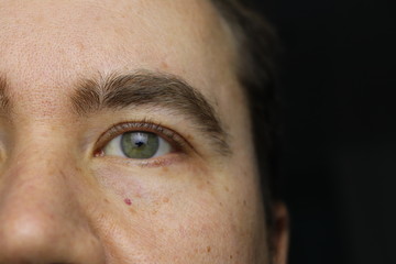 closeup portrait of a young man, one green eye