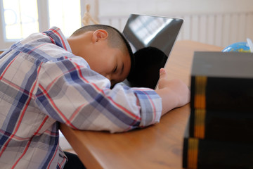 Wall Mural - lazy stressed young little asian kid boy  resting sleeping on desk. child fall asleep. children tired from studying in classroom.