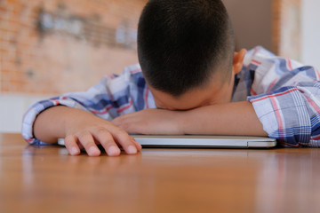 Wall Mural - lazy stressed young little asian kid boy  resting sleeping on desk. child fall asleep. children tired from studying in classroom.