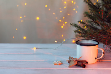 Wall Mural - mug with a hot drink in the light of the fireplace under the Christmas tree on the background of garlands atmosphere winter weekend