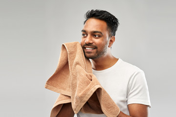 Wall Mural - grooming and people concept - smiling indian man with bath towel drying his face over grey background