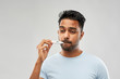 © Syda Productions - people, healthcare and fever concept - unhealthy indian man measuring oral temperature by thermometer over grey background