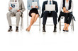 © LIGHTFIELD STUDIOS - low section view of businesspeople sitting on chairs with digital devices, newspaper and coffee cup, isolated on white