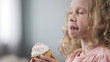 Adorable little girl eating cake with appetite enjoying perfect taste of dessert
