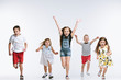 © master1305 - Group of fashion cute preschooler kids friends running together and looking at camera on a white studio background. The friendship, fashion, summer concept. Space for text.