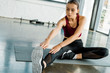 © LIGHTFIELD STUDIOS - concentrated sportswoman sitting on mat and doing stretching exercise at gym