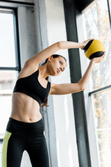 Wall Mural - focused beautiful sportswoman training and stretching with medicine ball at gym