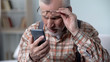 © motortion - Bewildered old man looking at cellphone, new technology complicated for elderly