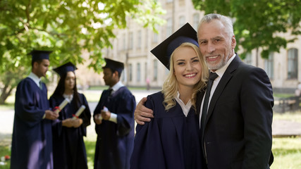 Wall Mural - Female graduate hugging dad and smiling into camera, successful future, career