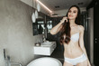 © Yakobchuk Olena - Portrait of glad beautiful female in white lingerie touching chin with hand while locating in bathroom