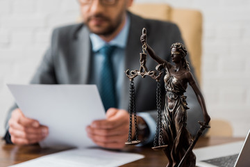 Canvas Print - close-up view of lady justice statue and lawyer working working with papers behind