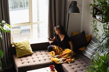 Woman Using Mobile Phone On Sofa In Living Room