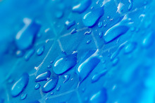 Water Drops On Waterproof Nylon Fabric. Macro Detail View Of Texture Of Blue Woven Synthetic Waterproof Clothing. Waterproof Fabric With Water Drops. Rain Drops On Water Resistant Textile.