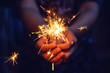 Woman hand holding a burning sparkler, Christmas and new year sparkler holiday background