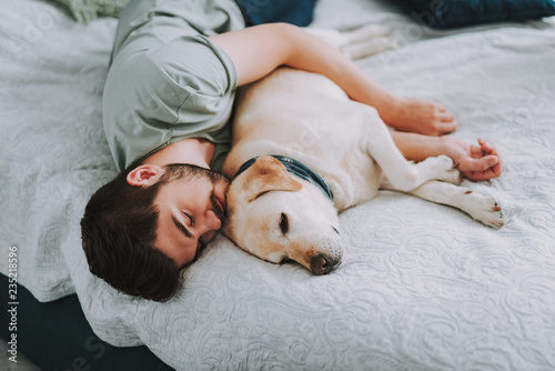 Fotomural Pleasant young man enjoying his sleep while embracing his dog
