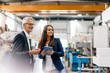 © Westend61 - Businessman an woman in high tech enterprise, having a meeting in factory workshop