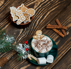 cup of hot cocoa with marshmallow, cookies, fir-tree on wooden background