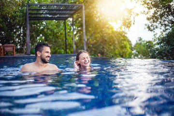 Wall Mural - young beautiful couple man and woman have fun in the outdoor pool, squabbles, vacation and holiday, youth, freedom and happiness