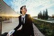 © mnelen.com - smiling young stewardess woman in uniform waiting for her plane, looking up at the sky, with suitcase
