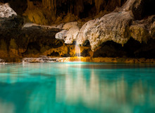 A Small Picturesque Waterfall In A Cave Falls Into A Warm Blue And Green Underground Hot Spring 
