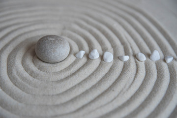 Gray zen stones on the sand with wave drawings. Concept of harmony, balance and meditation, spa, massage, relax