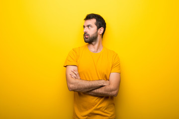 Wall Mural - Man on isolated vibrant yellow color with confuse face expression while bites lip