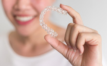A Smiling Woman Holding Invisalign Or Invisible Braces, Orthodontic Equipment