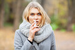 © Maksymiv Iurii - Cold and flu. Young sick woman uses a nose spray at street outside