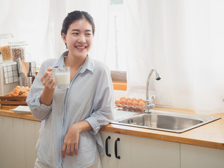 asian woman drink milk  in the kitchen