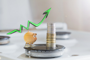 the concept of rising prices for utilities or gas.toy little pig on the background of coins and growth charts on the gas stove