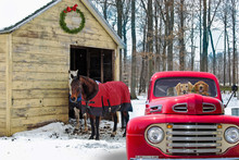 Red Retro Pickup Truck And Horses By Rural Barn In Winter With Christmas Wreath