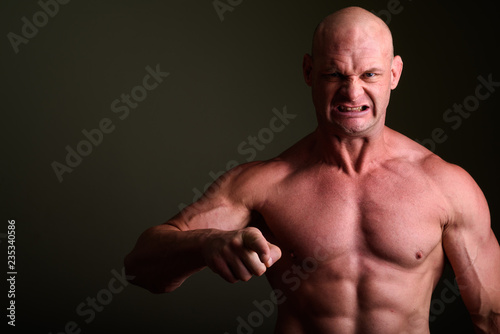Fotografie, Obraz Bald muscular man shirtless against colored background