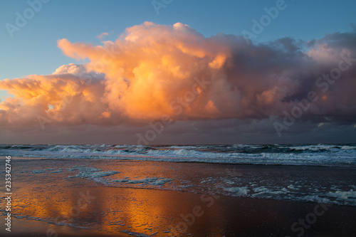 Plakat Przednia burza zbliża się nad morzem po zachodzie słońca: zagrażające czerwone chmury nad ciemną wodą