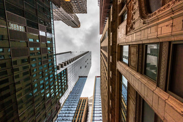 Wide-angle view looking up through tall buildings and skyscrapers in downtown Chicago Illinois