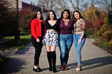 Wall Mural - Group of four happy and pretty latino girls from Ecuador posed at street.