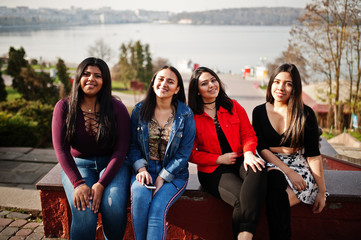 Wall Mural - Group of four happy and pretty latino girls from Ecuador posed at street.