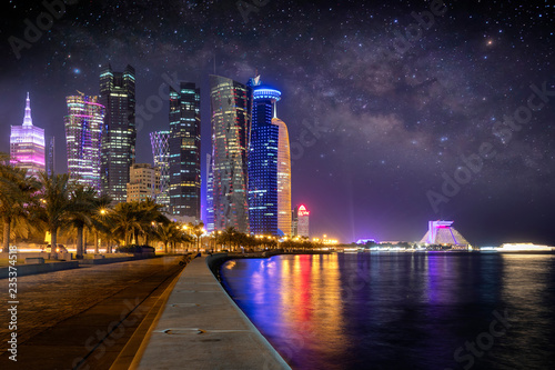 Fototapeta Oświetlone miasto Doha w Emiracie w Katarze wieczorem z rozgwieżdżonym niebem