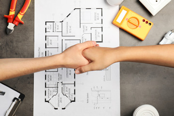 Sticker - Electrician and client shaking hands over table with house plan