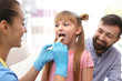 Children's doctor examining little girl's throat at home