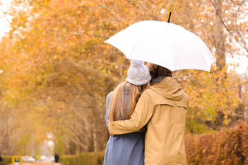 Sticker - Young romantic couple with umbrella in park on autumn day