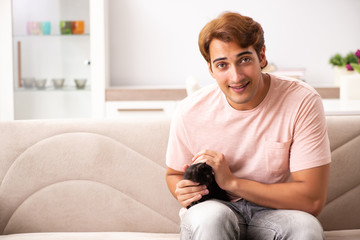 Young man playing with kitten at home