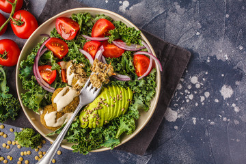 Vegan lentil meatballs salad with kale, avocado, tomato and tahini dressing.